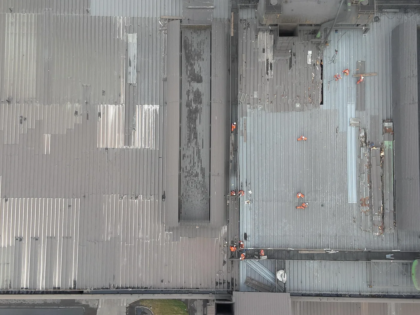 Vista aérea da cobertura com a equipe de laranja na frente de troca das telhas
