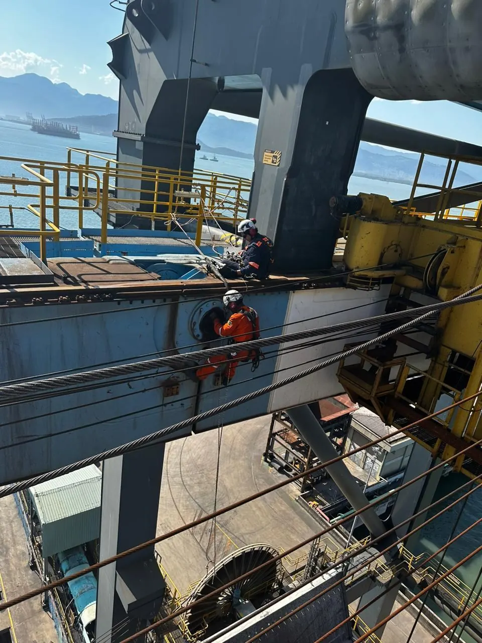 Equipe em manutenção de viga metálica sobre o pátio do terminal